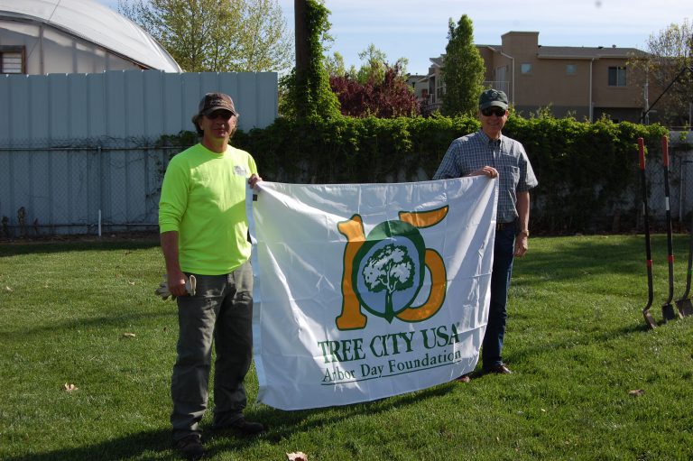 Garden City Arbor day. Two men holding a Tree City USA Arbor Day Foundation banner.
