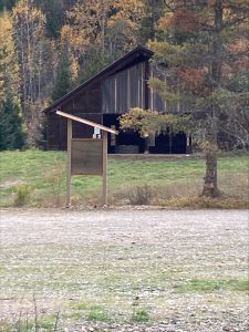 Wood kiosk in open area in front of wood structure and forest